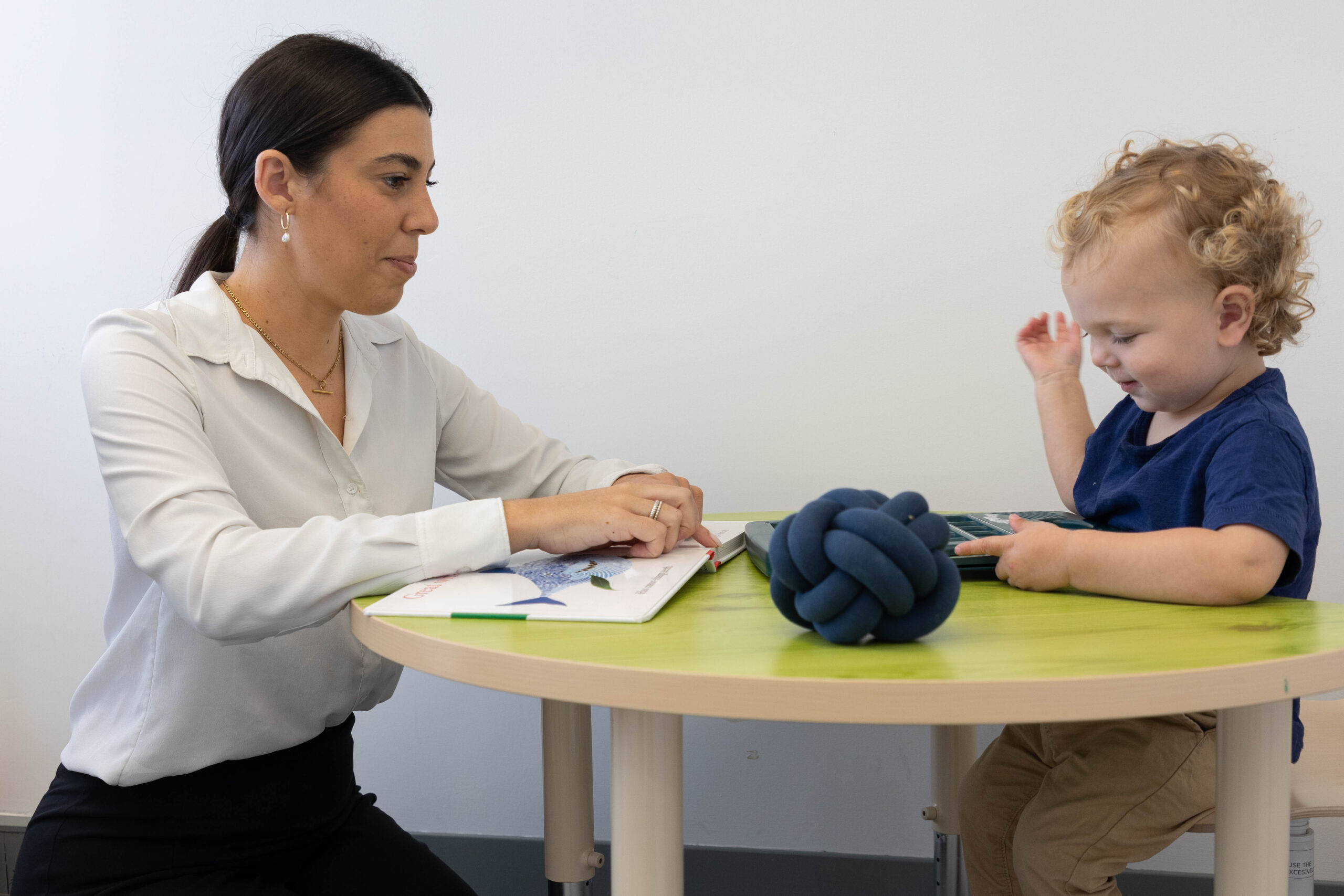 A woman and a young child are seated at a small table.