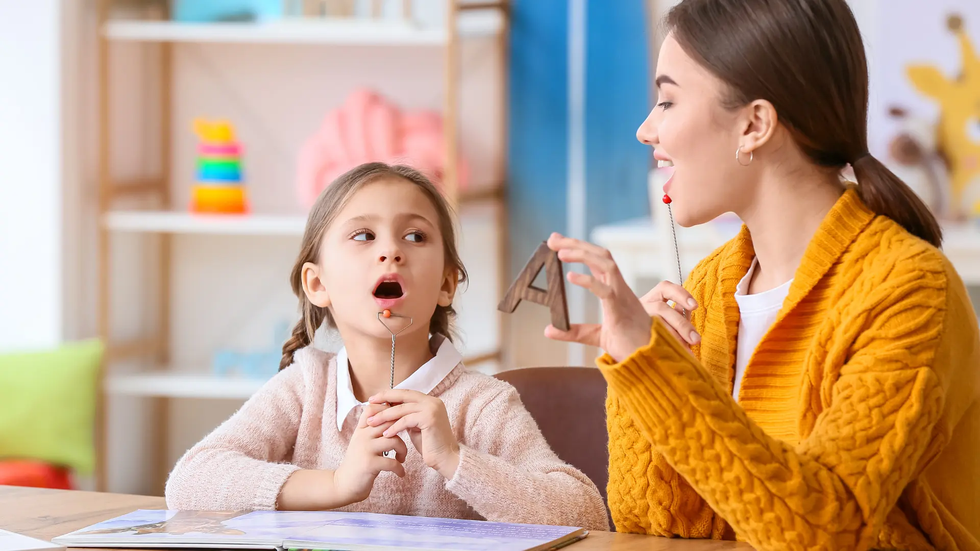 A young girl practicing speech therapy exercises with a female therapist